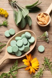Photo of Different pills, herbs and flowers on wooden table, flat lay. Dietary supplements