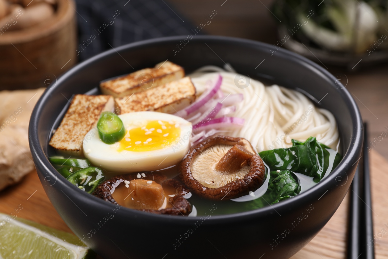 Photo of Delicious vegetarian ramen in bowl on wooden table, closeup