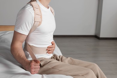 Photo of Closeup view of man with orthopedic corset sitting in room