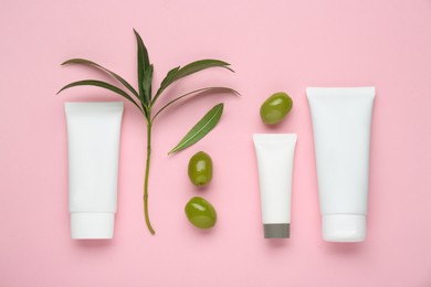 Photo of Tubes of natural cream with olive essential oil on pink background, flat lay