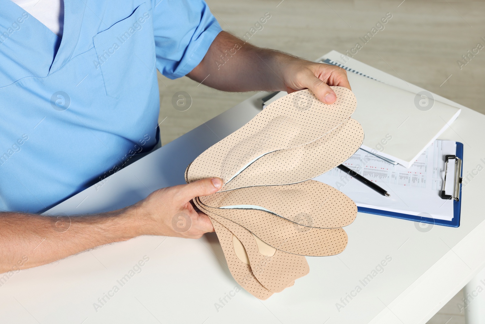 Photo of Male orthopedist showing insoles in hospital, closeup