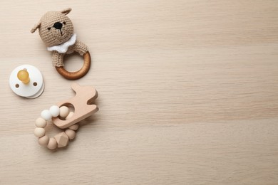 Photo of Cute baby toys and pacifier on wooden background, flat lay. Space for text