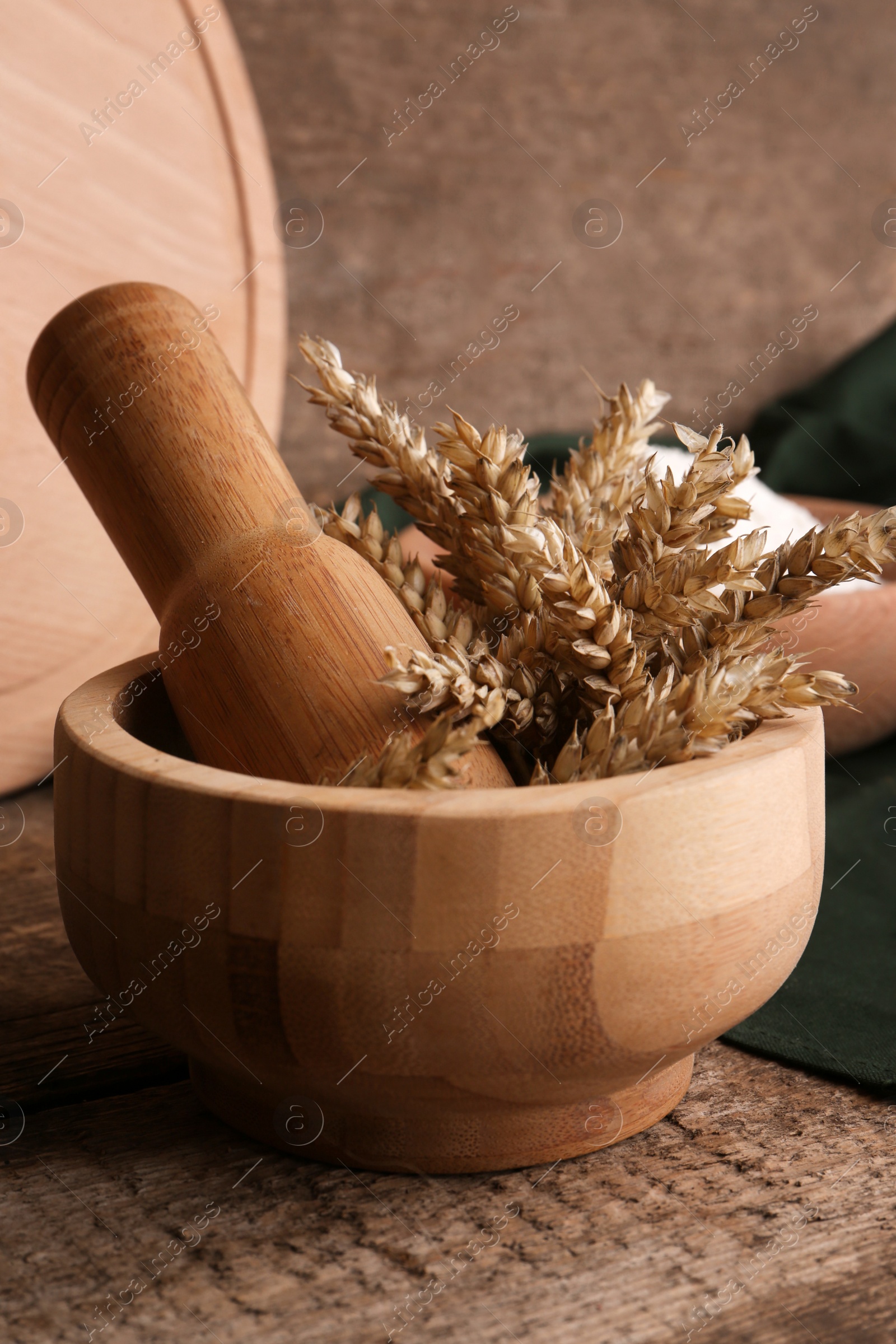 Photo of Mortar with wheat spikes on wooden table