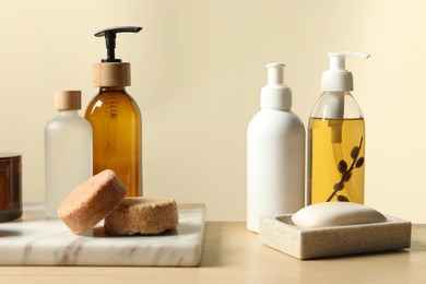 Photo of Different bath accessories on wooden table against beige background, closeup