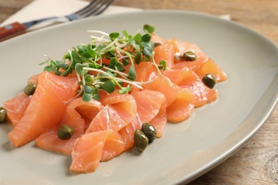 Photo of Delicious salmon carpaccio served on wooden table, closeup