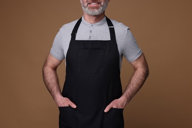 Photo of Man wearing kitchen apron on brown background, closeup. Mockup for design