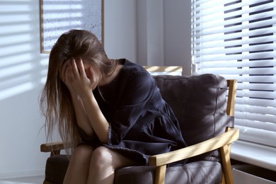 Photo of Abused young woman crying indoors. Domestic violence concept