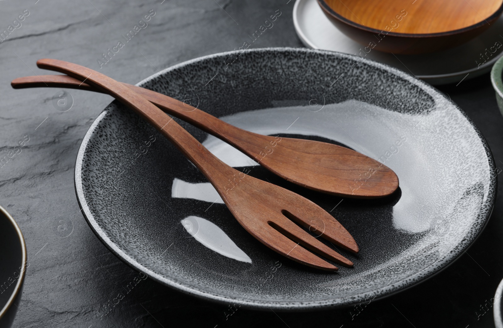 Photo of Set of clean tableware on black table, closeup