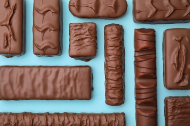 Photo of Different tasty chocolate bars on light blue background, flat lay