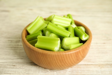 Cut celery in bowl on white wooden table