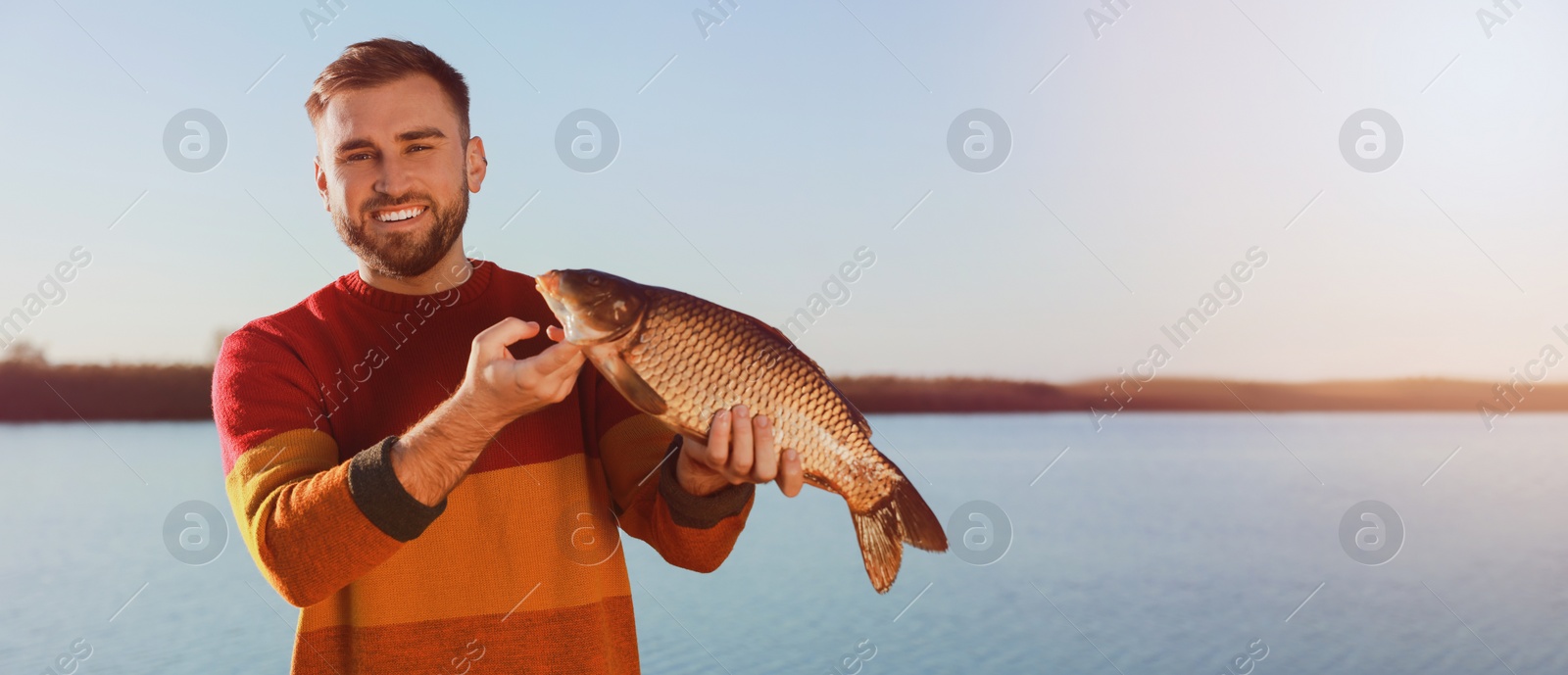 Image of Fisherman holding caught fish at riverside, space for text. Banner design