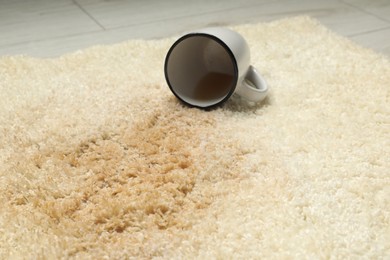 Overturned cup and spilled drink on beige carpet, closeup
