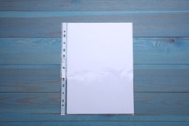 Photo of Punched pocket with paper sheet on light blue wooden table, top view