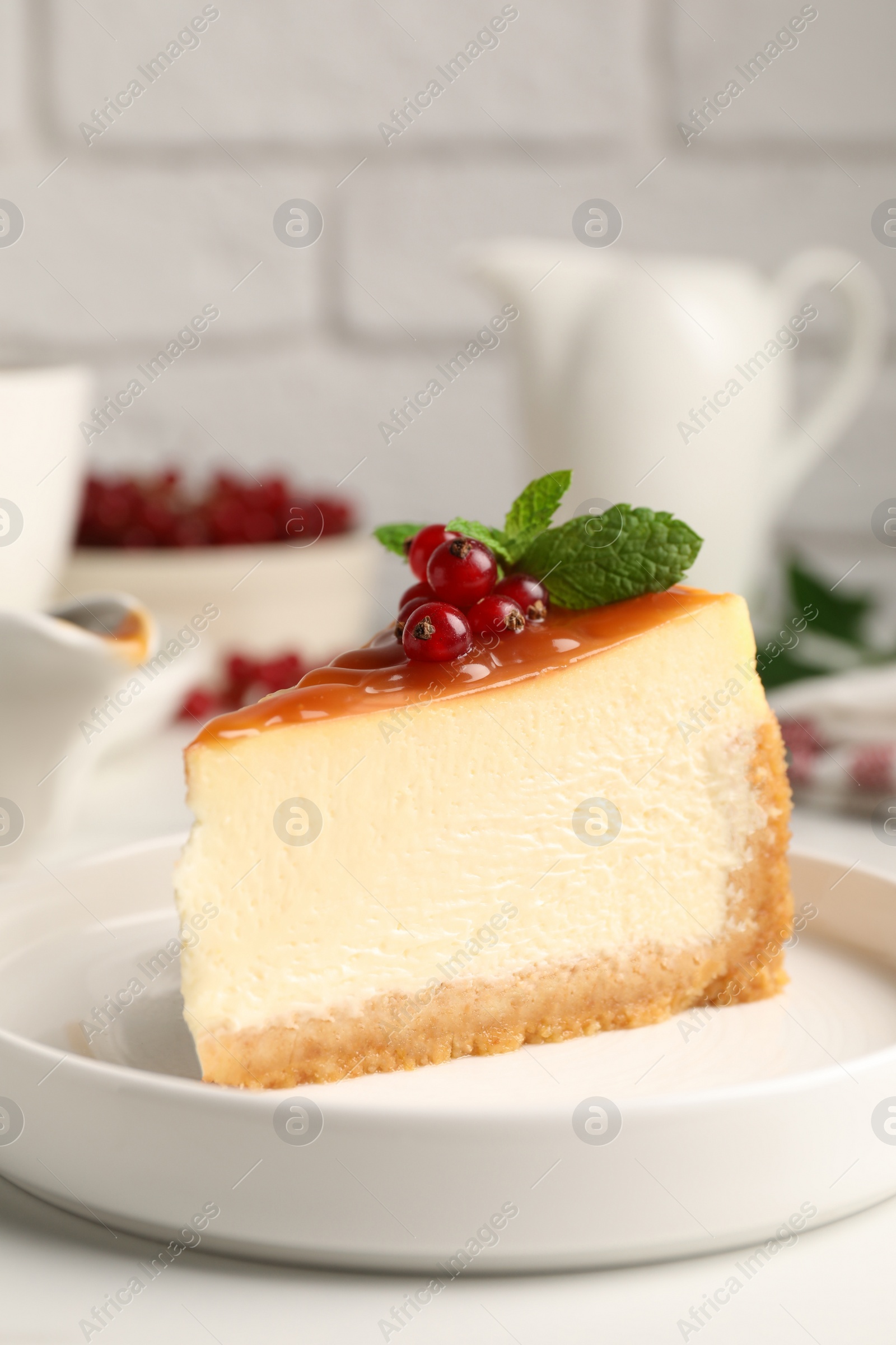 Photo of Piece of delicious caramel cheesecake with red currants and mint served on white marble table