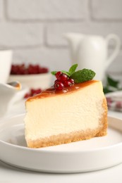 Photo of Piece of delicious caramel cheesecake with red currants and mint served on white marble table
