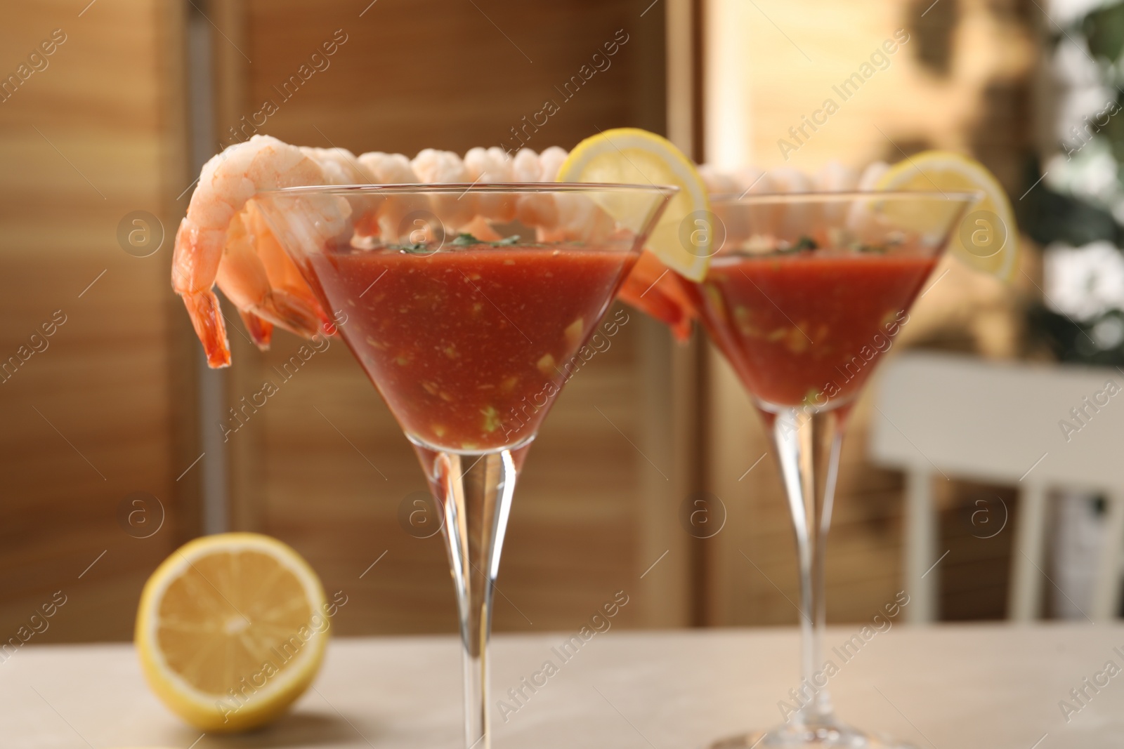 Photo of Tasty shrimp cocktail with sauce in glasses and lemon on light table