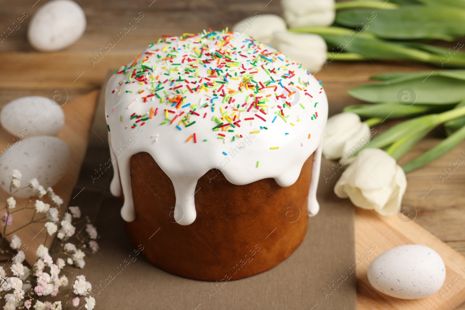 Photo of Tasty Easter cake, decorated eggs and flowers on wooden table