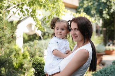 Happy mother with her cute daughter spending time together in park