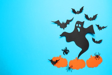 Photo of Flat lay composition with paper ghost, bats and pumpkins on light blue background, space for text. Halloween celebration