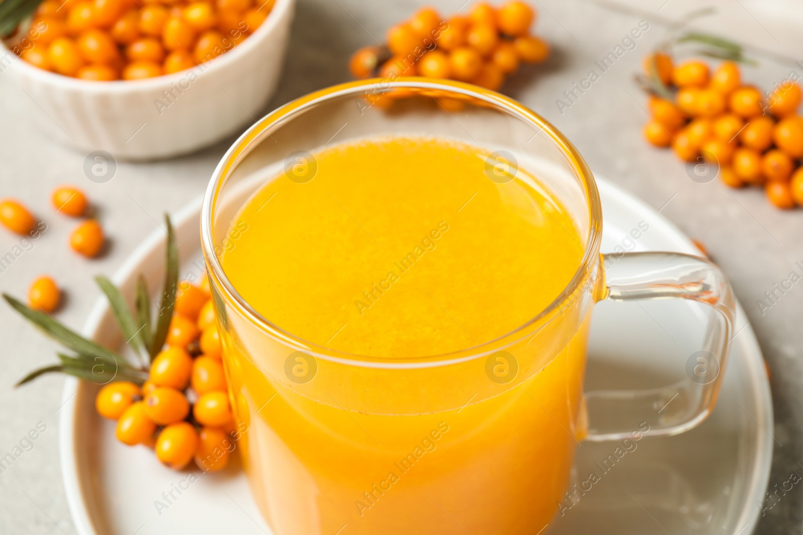 Photo of Delicious sea buckthorn tea in glass cup on table, closeup