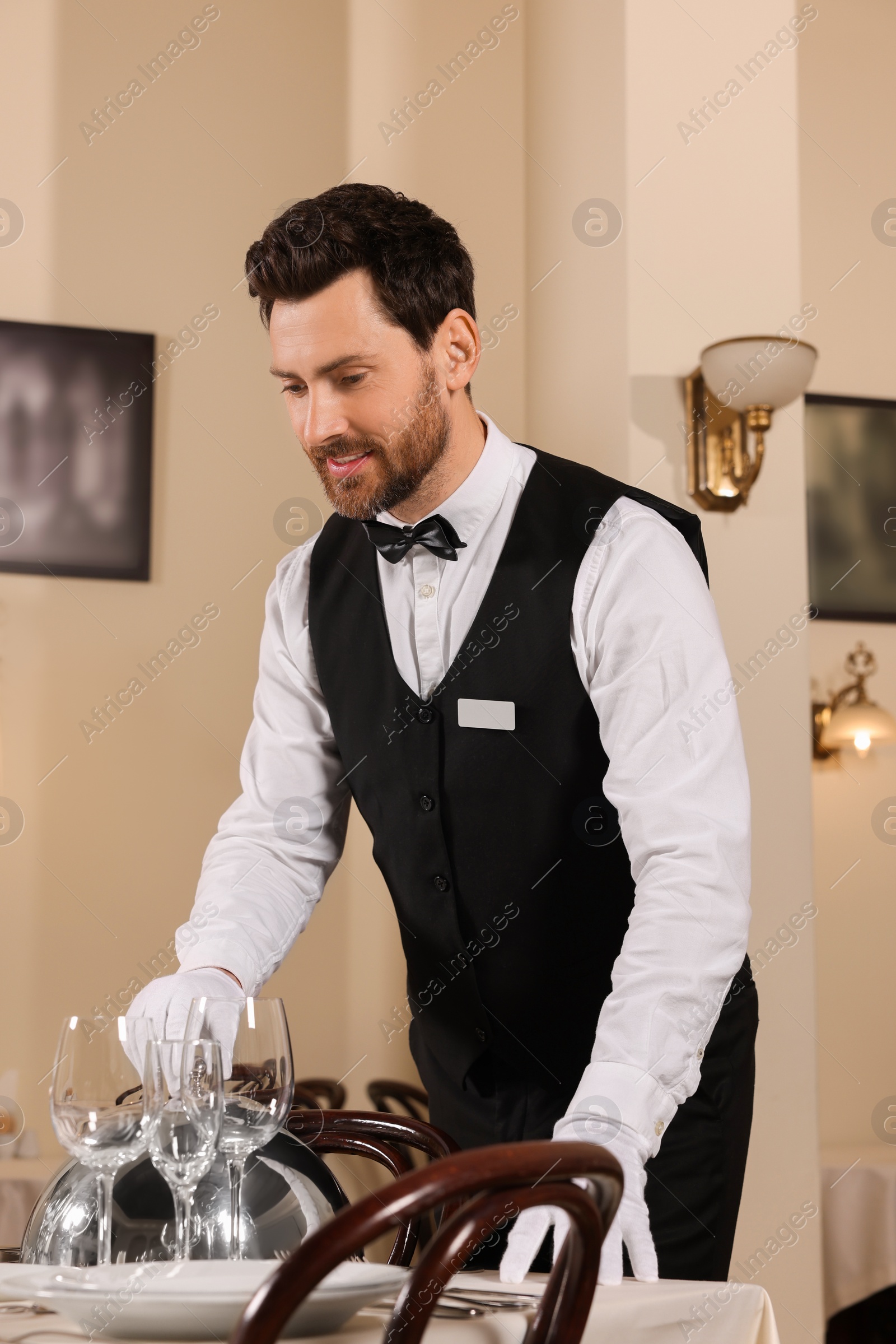 Photo of Man setting table in restaurant. Professional butler courses