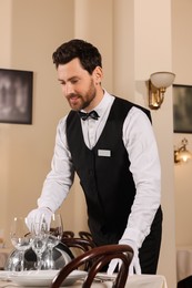 Photo of Man setting table in restaurant. Professional butler courses