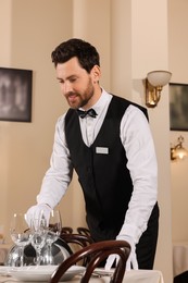 Man setting table in restaurant. Professional butler courses