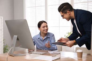 Businessman helping intern with work in office