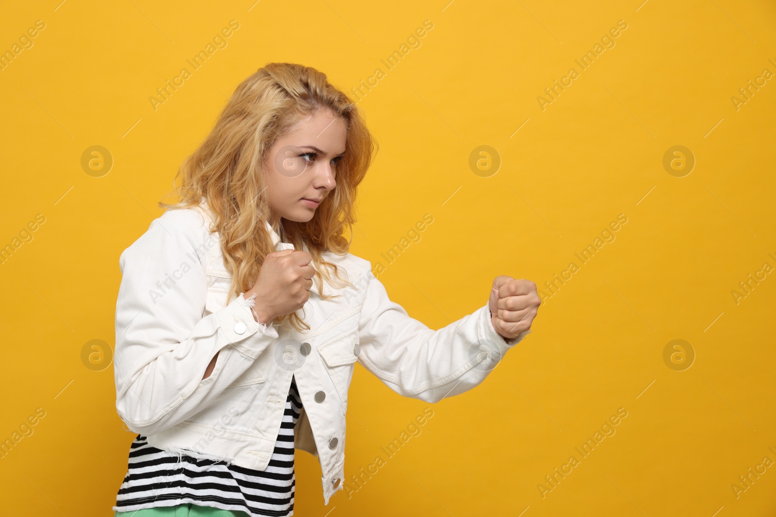 Photo of Young woman ready to fight on yellow background. Space for text