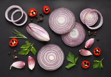 Flat lay composition with cut onion and spices on black background