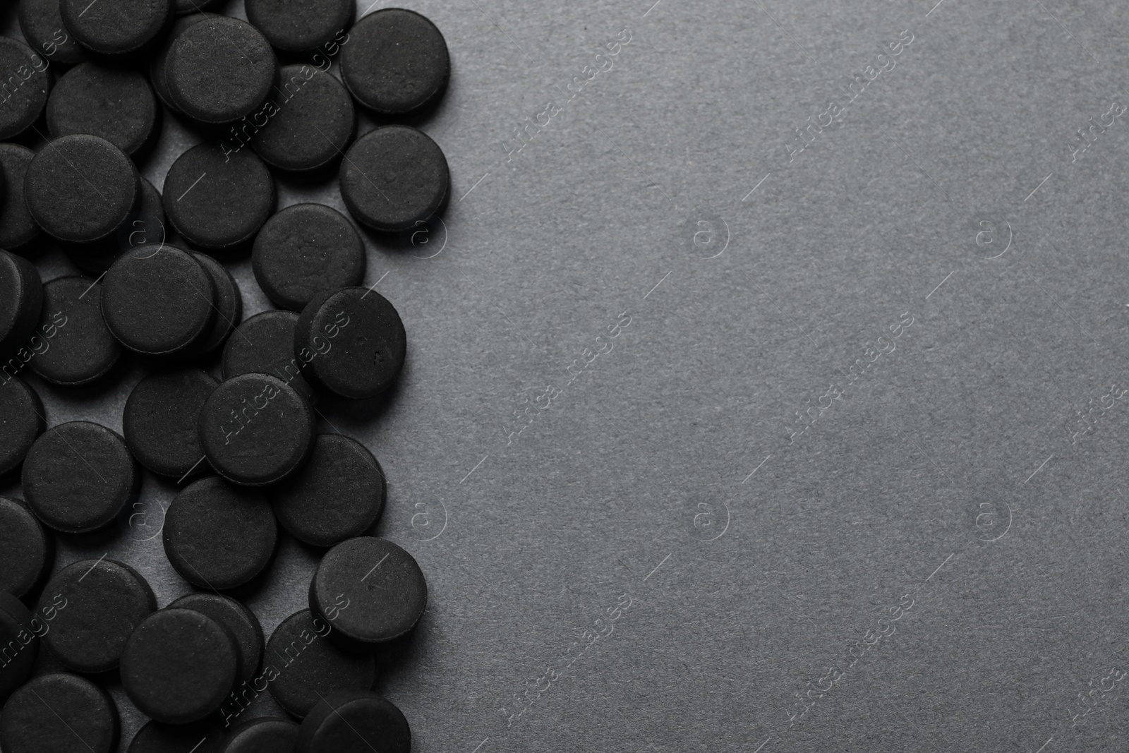 Photo of Activated charcoal pills on grey background, flat lay with space for text. Potent sorbent