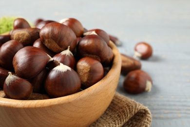 Fresh sweet edible chestnuts in wooden bowl, closeup