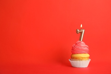 Photo of Birthday cupcake with number seven candle on red background, space for text