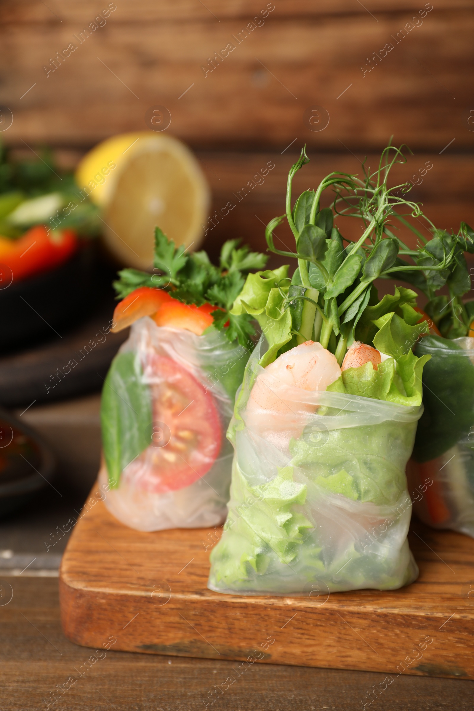 Photo of Many different delicious rolls wrapped in rice paper on wooden table