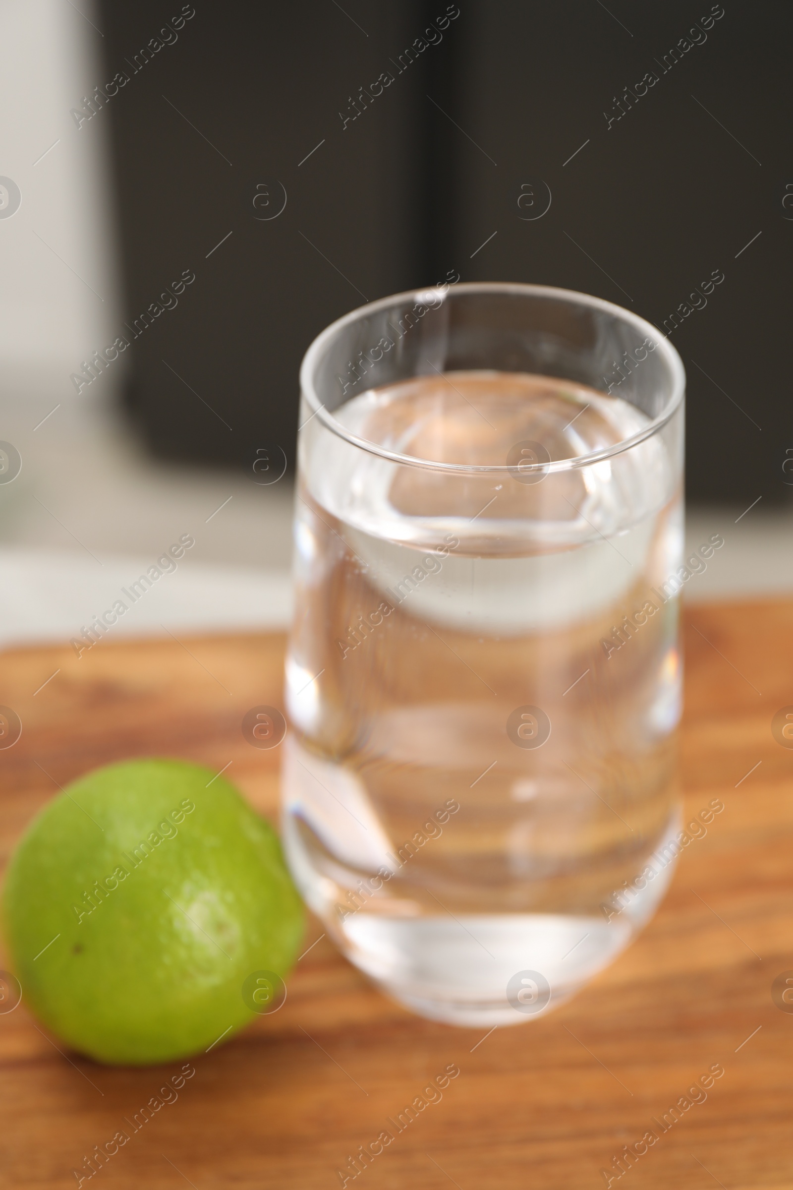 Photo of Filtered water in glass and lime on table in kitchen, closeup