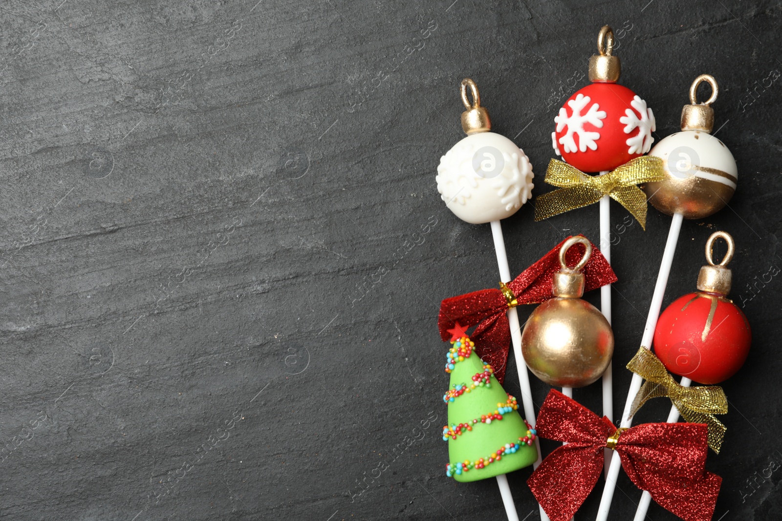 Photo of Delicious Christmas themed cake pops on black table, flat lay. Space for text