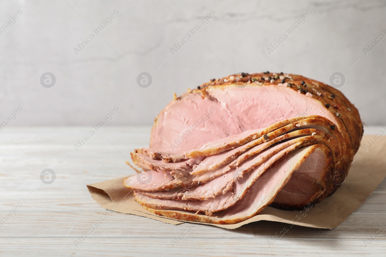 Photo of Delicious sliced baked ham on white wooden table. Space for text