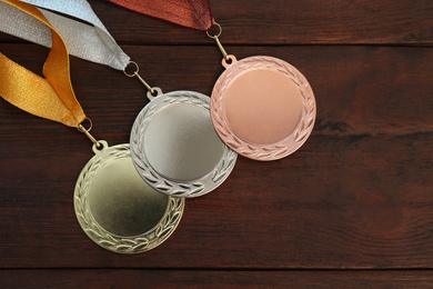 Photo of Gold, silver and bronze medals on wooden background, flat lay. Space for design