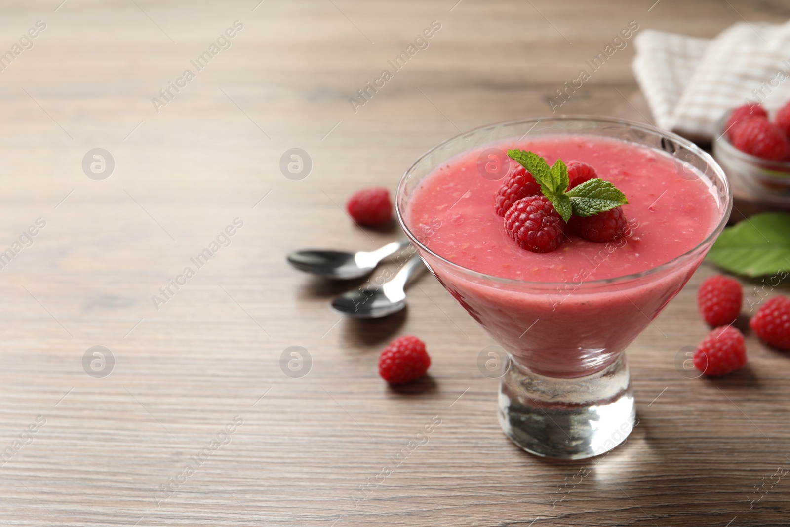 Photo of Delicious raspberry mousse with mint on wooden table, space for text