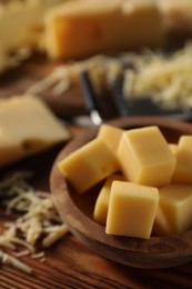 Grated and cut cheese on wooden table, closeup