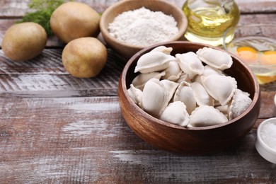 Photo of Raw dumplings (varenyky) and ingredients on wooden table, space for text