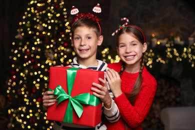 Portrait of happy children with Christmas gift at home