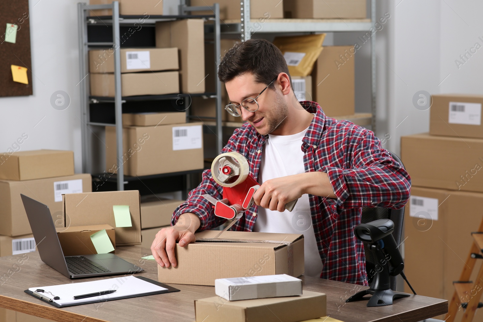 Photo of Seller taping parcel at workplace in office. Online store