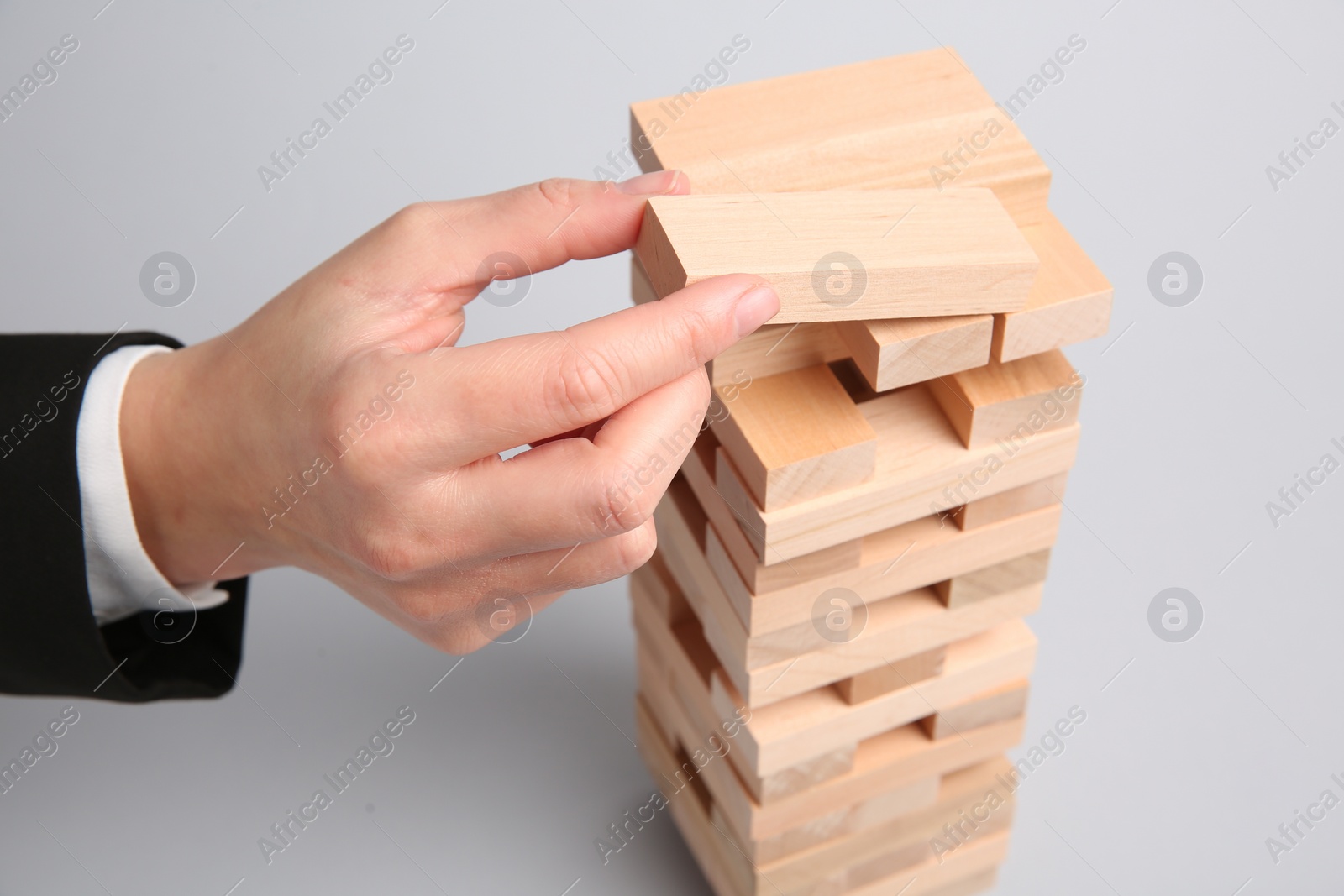 Photo of Woman playing Jenga on light gray background, closeup