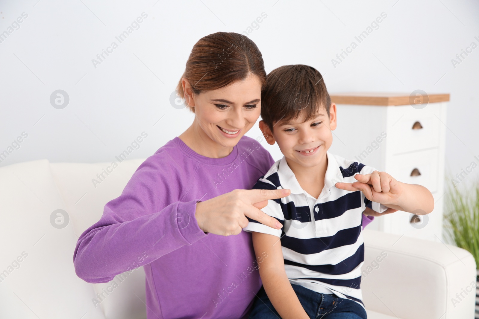 Photo of Hearing impaired mother and her child talking with help of sign language indoors