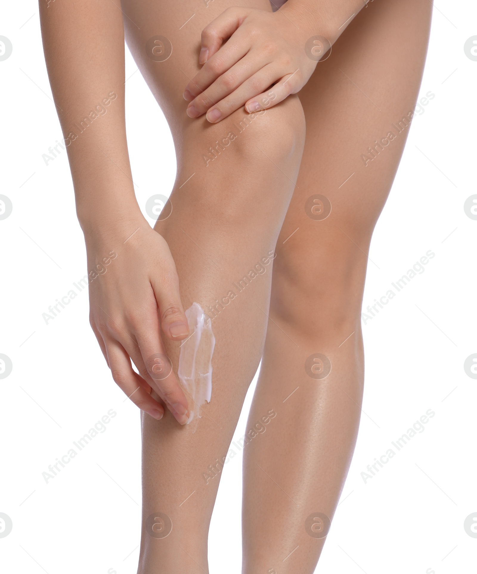 Photo of Woman applying body cream onto legs on white background, closeup