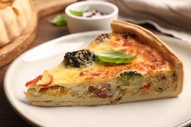 Photo of Piece of delicious homemade vegetable quiche on plate, closeup