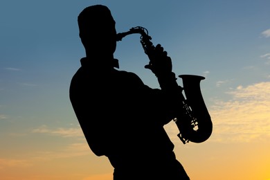 Image of Silhouette of man playing saxophone against beautiful sky at sunset