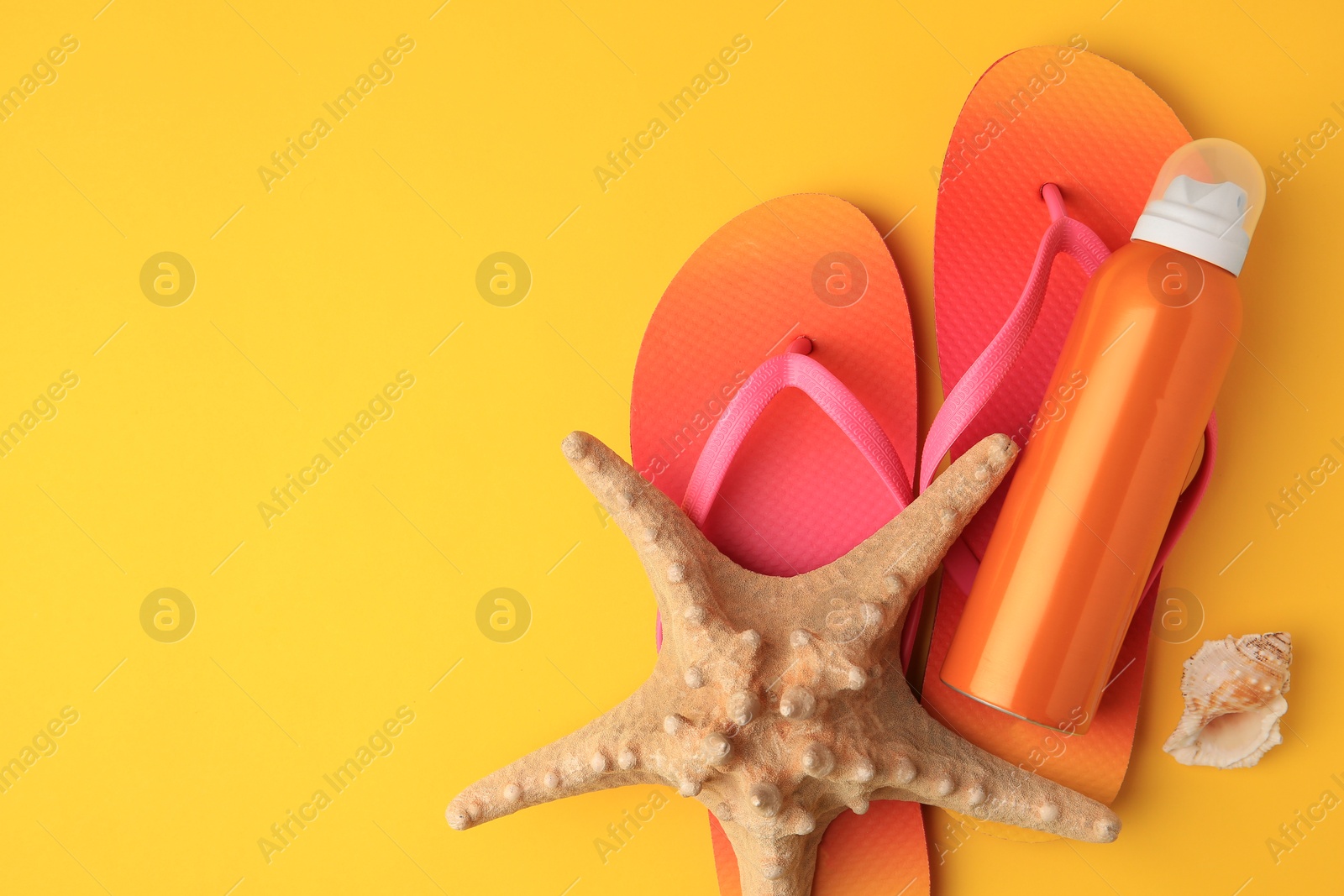 Photo of Sunscreen, starfish, shell and flip flops on orange background, flat lay with space for text. Sun protection