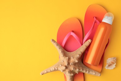 Sunscreen, starfish, shell and flip flops on orange background, flat lay with space for text. Sun protection